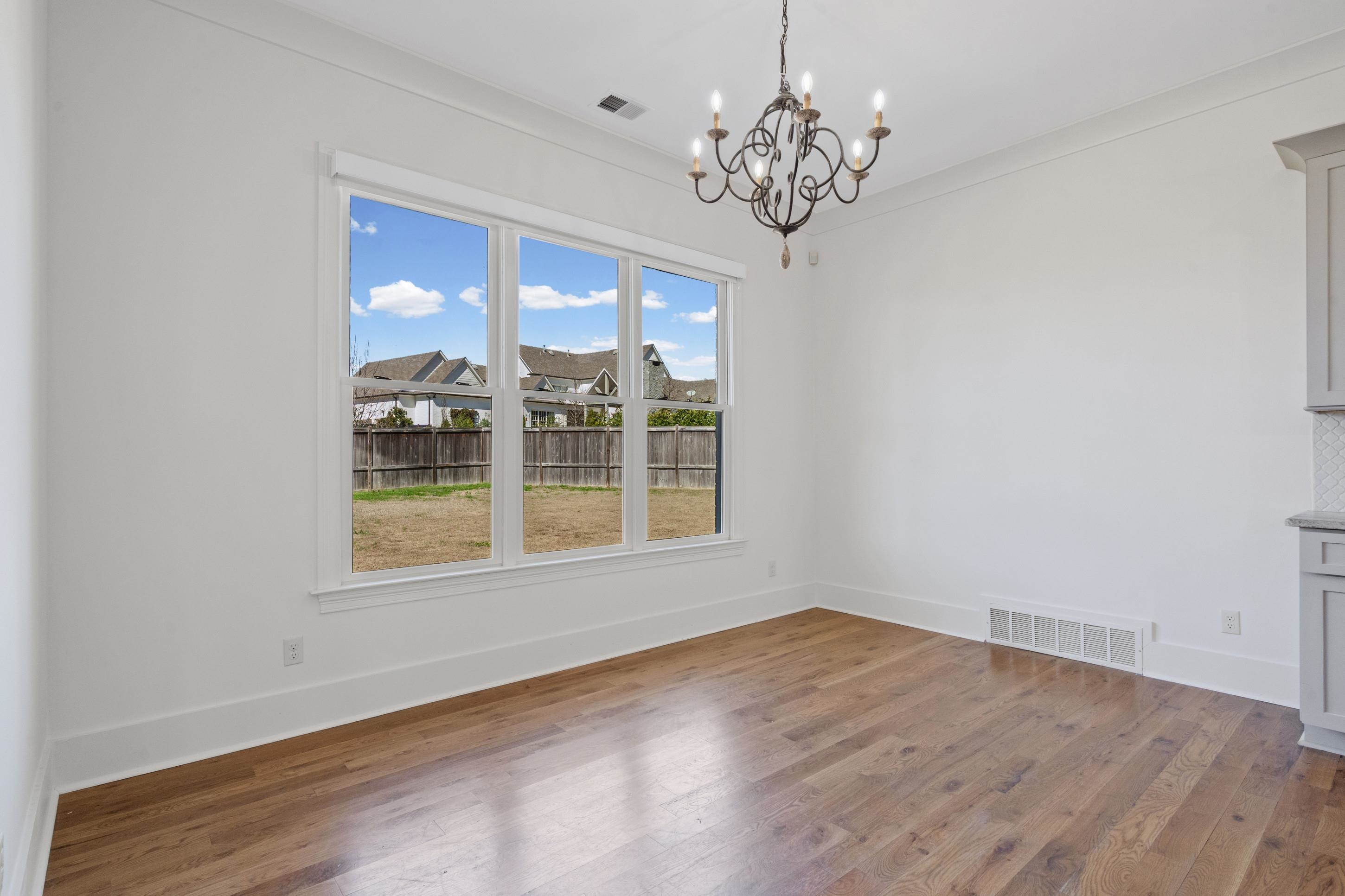 12608 Bravo Road Collierville, TN 38017 - Photo 24 of 40 Unfurnished dining area featuring hardwood / wood-style flooring, a chandelier, a residential view, and ornamental molding