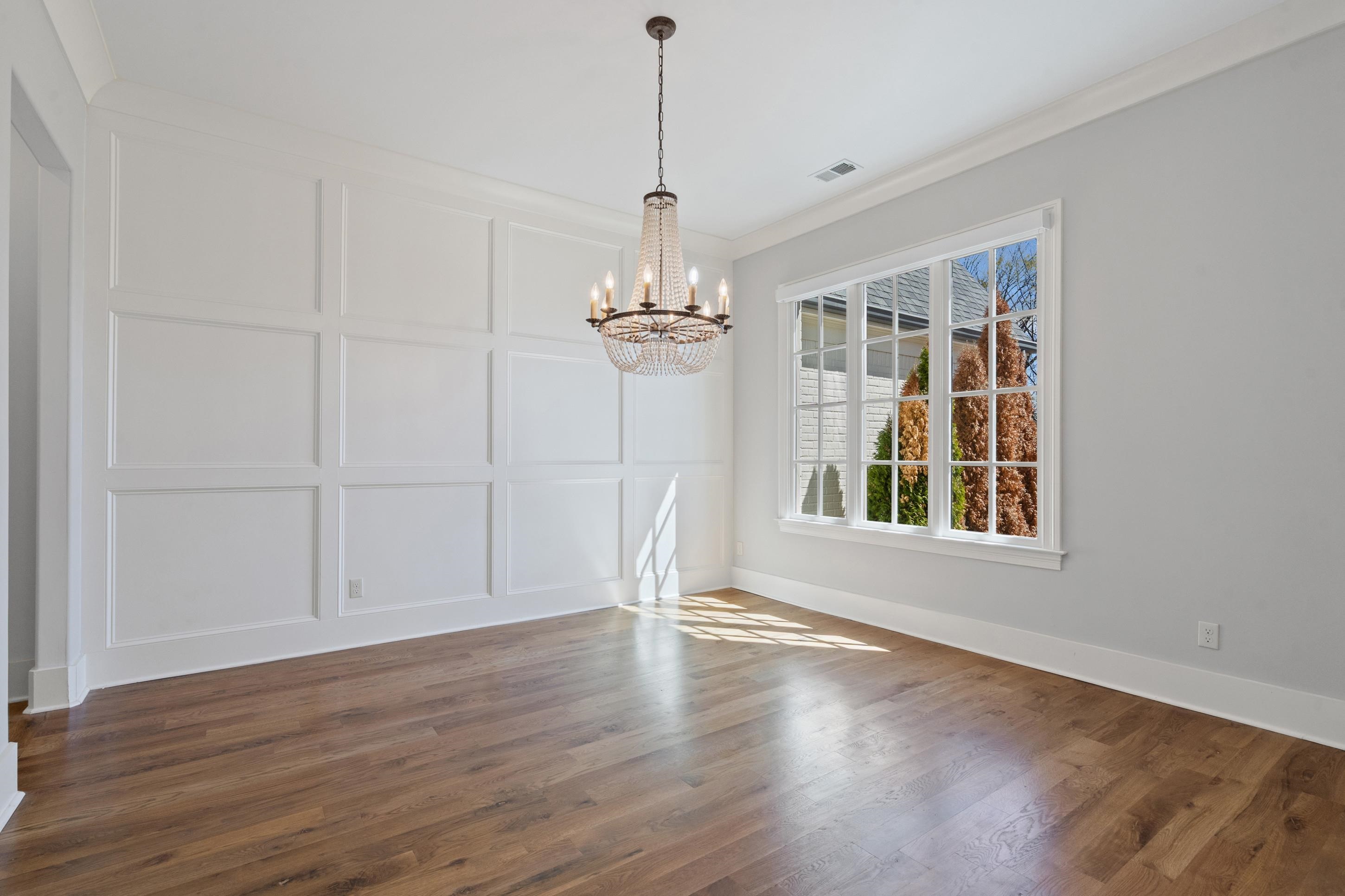 12608 Bravo Road Collierville, TN 38017 - Photo 5 of 40 Unfurnished dining area featuring a decorative wall, a chandelier, dark wood-type flooring, and crown molding
