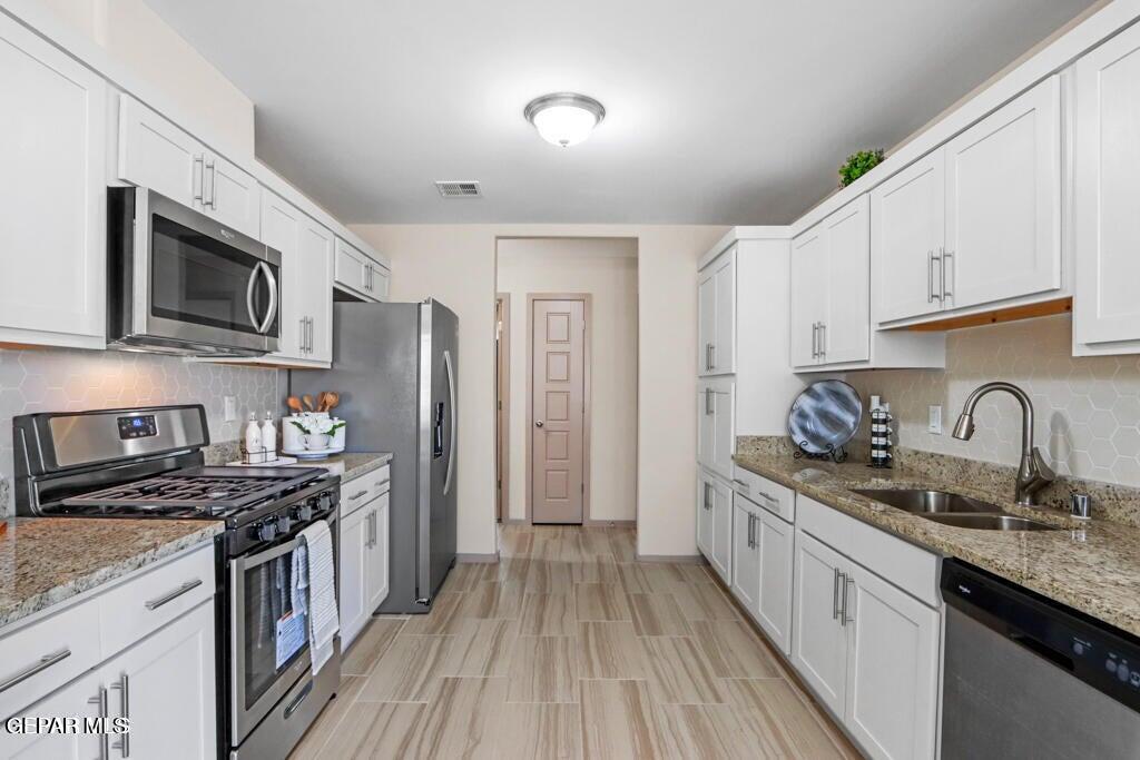 15040 Function Court El Paso, TX 79928 - Photo 4 of 10 a kitchen with stainless steel appliances granite countertop a stove top oven a sink dishwasher a refrigerator and cabinets with wooden floor
