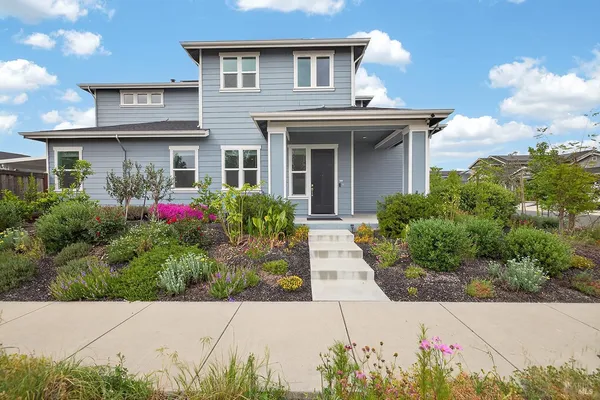 a view of a white house with potted plants