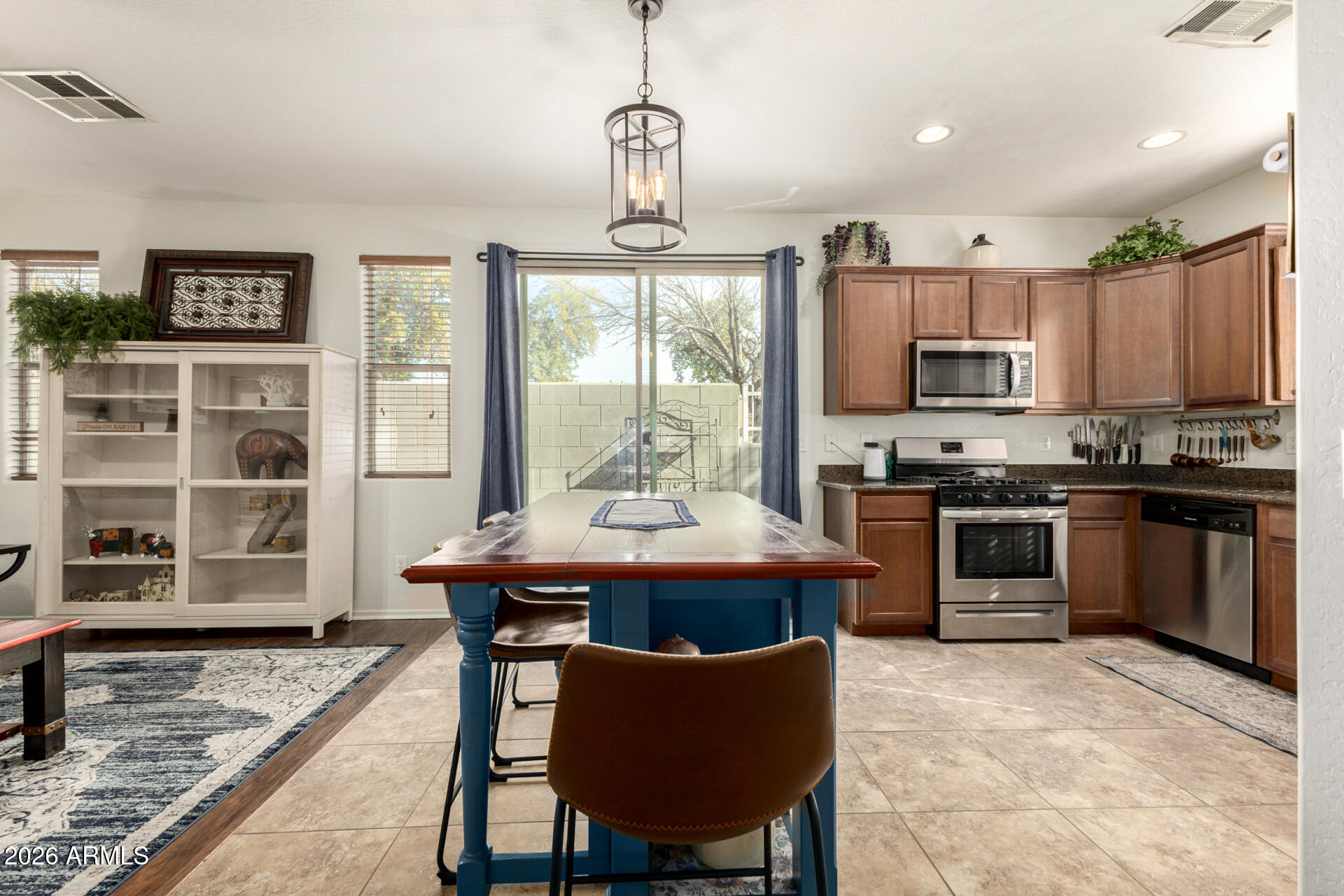1849 South Balboa Drive Gilbert, AZ 85295 - Photo 7 of 35 a kitchen with stainless steel appliances kitchen island granite countertop a stove a refrigerator a sink a dining table and chairs with wooden floor