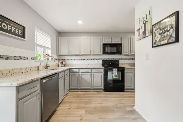 a kitchen with stainless steel appliances granite countertop a stove top oven a sink and dishwasher with wooden floor