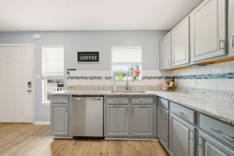 a kitchen with stainless steel appliances granite countertop a sink and dishwasher a stove top oven with wooden floor