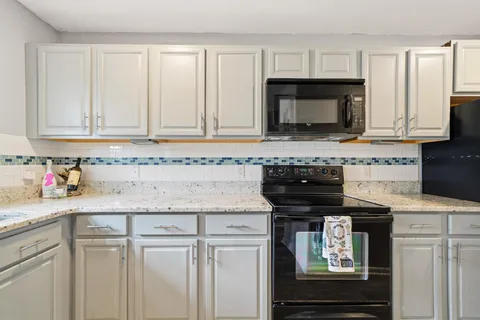 a kitchen with stainless steel appliances granite countertop a stove a sink and a microwave