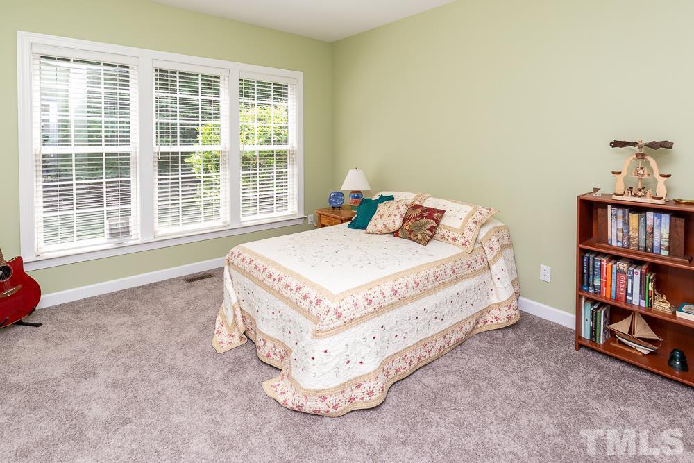 5116 Bartons Enclave Lane Raleigh, NC 27613 - Photo 11 of 30 a bed sitting in a bedroom next to a book shelf