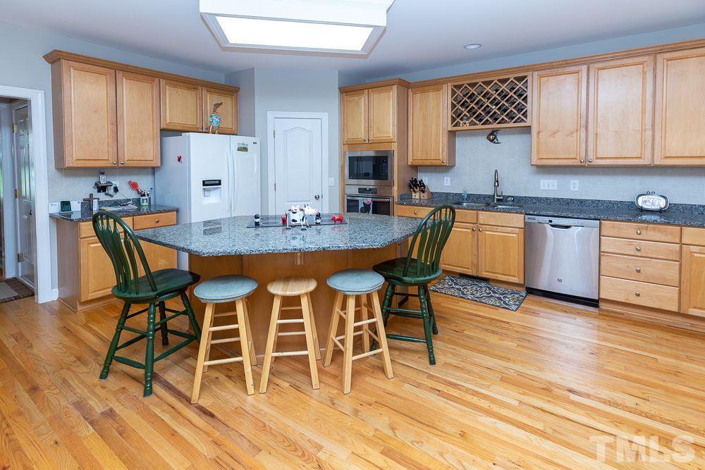 5116 Bartons Enclave Lane Raleigh, NC 27613 - Photo 6 of 30 a kitchen with granite countertop a dining table chairs and white cabinets