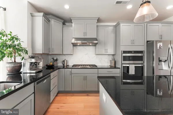a kitchen that has a lot of cabinets a sink and a wooden floor