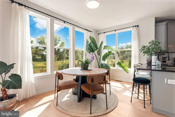 a dining room with furniture a potted plant and a large window