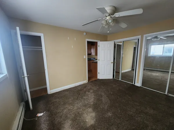 an empty room with closet and a ceiling fan