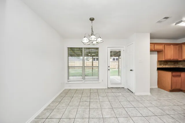 a view of an empty room with window and chandelier fan