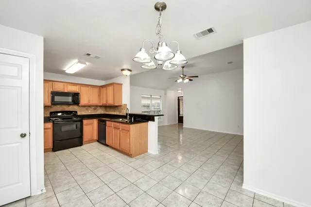 a large kitchen with granite countertop a stove a sink dishwasher and a refrigerator with wooden floor