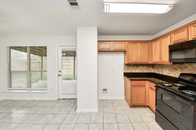 a kitchen with granite countertop a stove a sink and a refrigerator