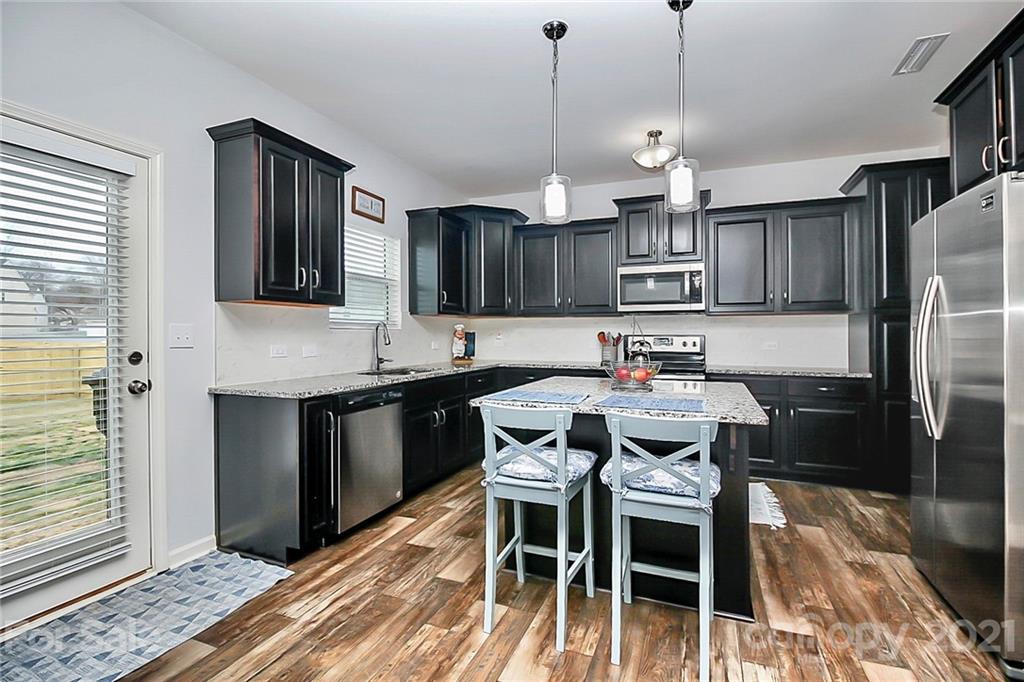 3034 Riker Street Clover, SC 29710 - Photo 12 of 42 a kitchen with stainless steel appliances granite countertop a stove a refrigerator a sink a dining table and chairs with wooden floor