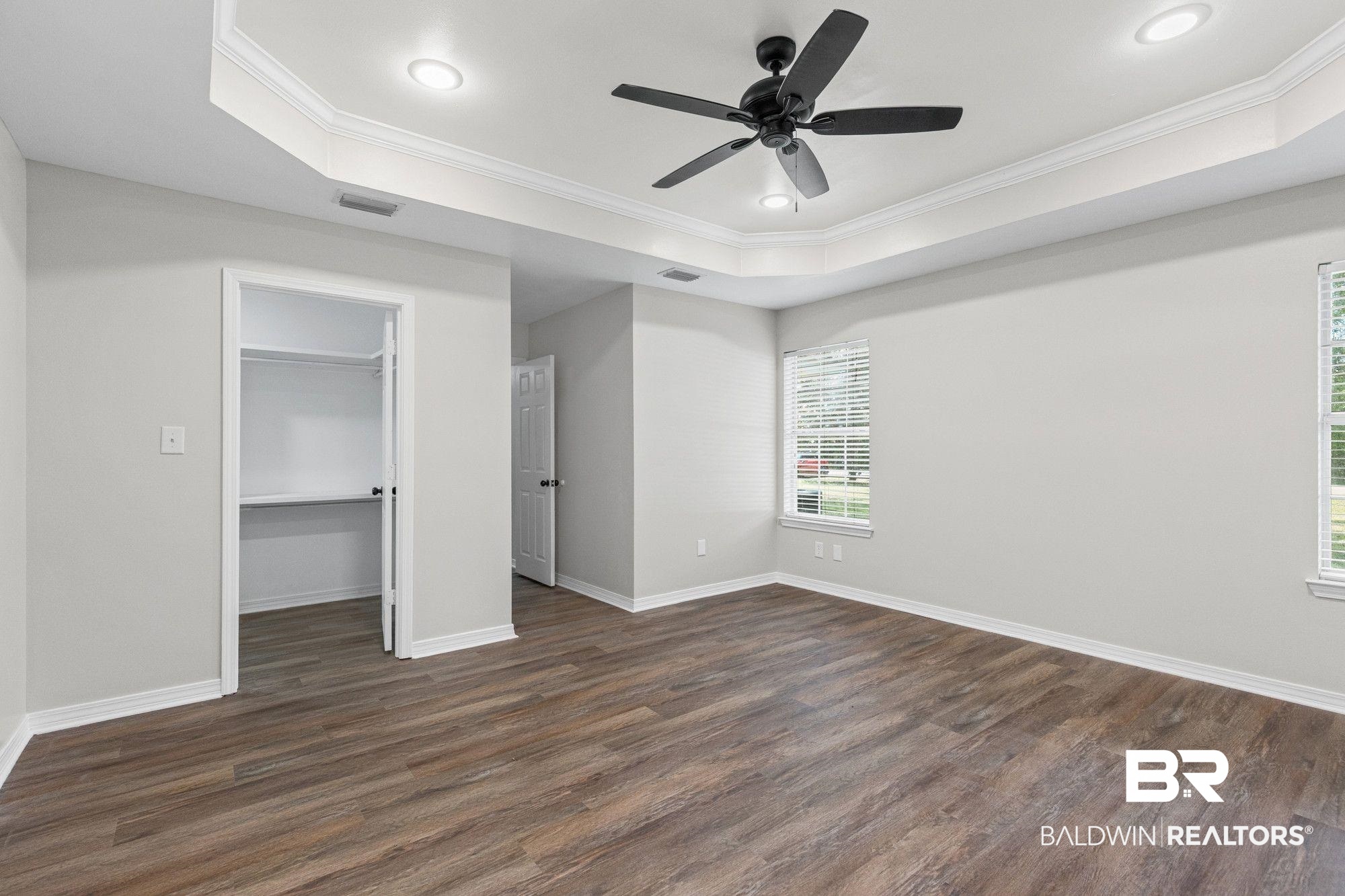 1301 Repoll Road Mobile, AL 36695 - Photo 11 of 21 Spacious room featuring wood-finish flooring, a tray ceiling with recessed lighting, and a matte black ceiling fan