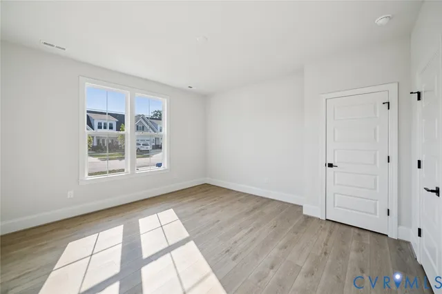 a view of an empty room with a window and wooden floor