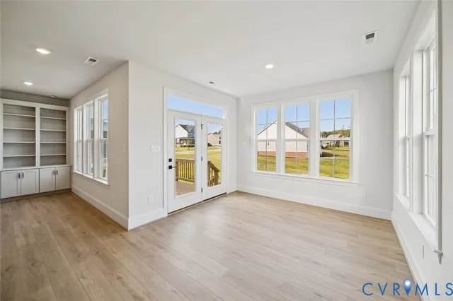 a view of an empty room with a window and wooden floor