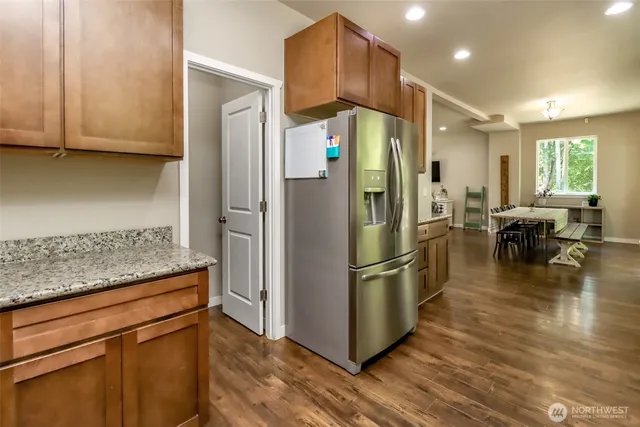 a kitchen with stainless steel appliances granite countertop a refrigerator a stove and a wooden floors