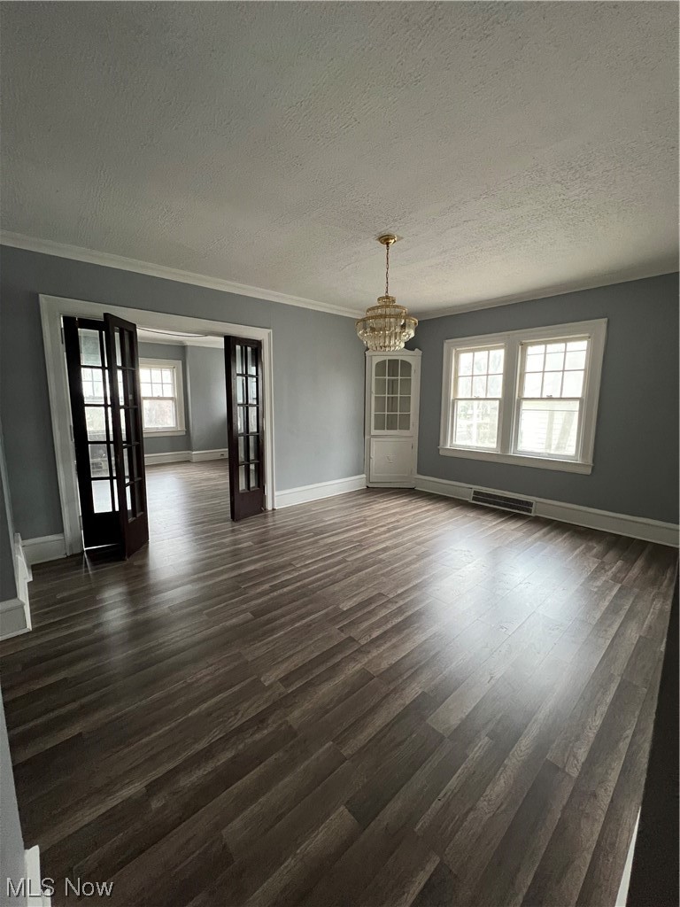 1717 Compton Road Cleveland Heights, OH 44118 - Photo 10 of 24 Unfurnished room featuring a chandelier, a textured ceiling, dark wood-type flooring, ornamental molding, and french doors