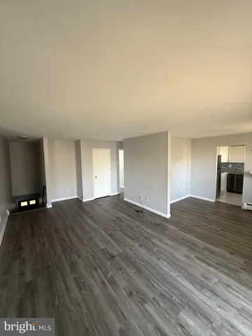 a view of empty room with wooden floor and window