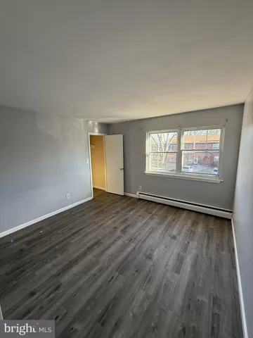 a view of an empty room with wooden floor and window