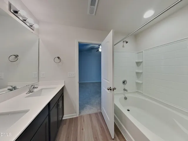 a bathroom with a tub sink double vanity granite tub shower and mirror