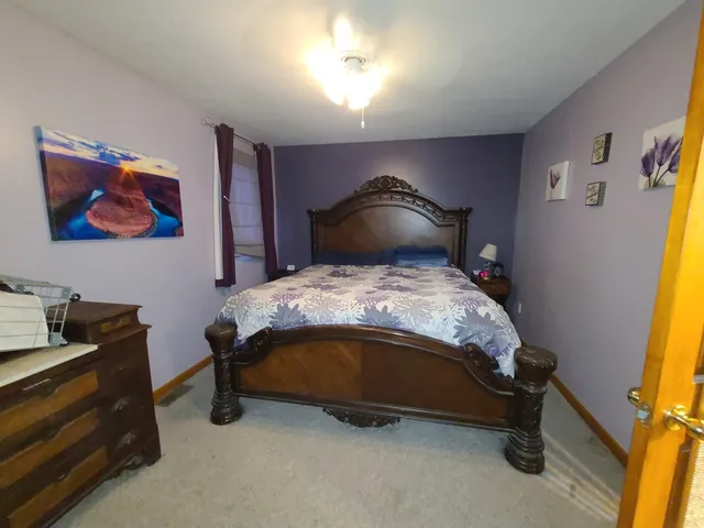 a bed sitting in a room next to a lamp with a workspace