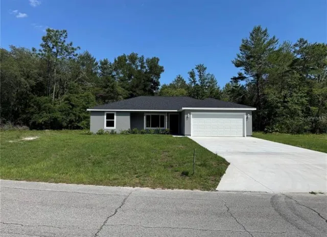 a front view of a house with a yard and trees