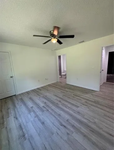 a view of a room with wooden floor ceiling fan and window