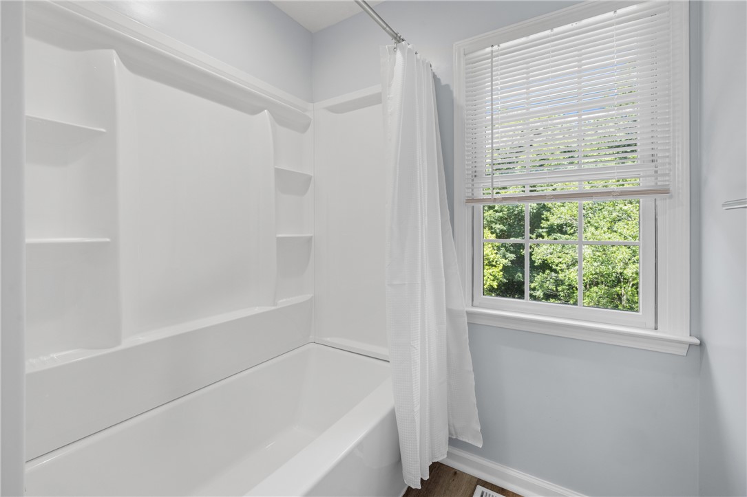 429 Burns Mill Road West Union, SC 29696 - Photo 26 of 49 A well-lit bathroom features a classic shower-tub combination and a bright window offering leafy views.