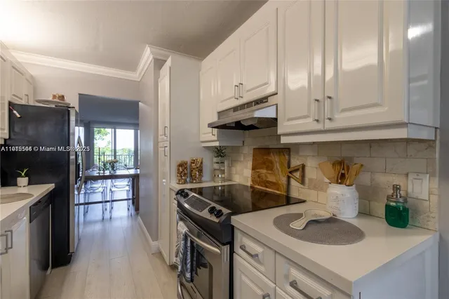 a kitchen with kitchen island granite countertop a sink a counter space appliances and cabinets