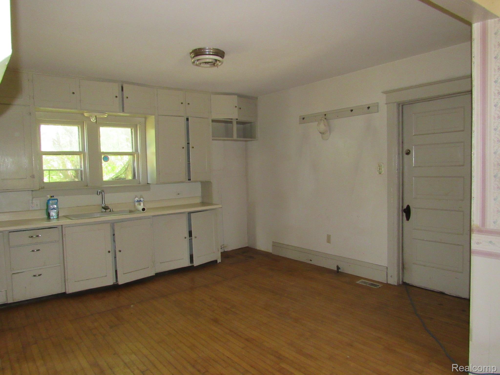 695 Cass Avenue Road Bay City, MI 48708 - Photo 9 of 52 Kitchen area featuring wood-finish flooring, white cabinetry, integrated sink, and dual windows