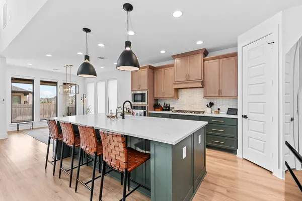 a kitchen with stainless steel appliances kitchen island granite countertop a table chairs sink and cabinets