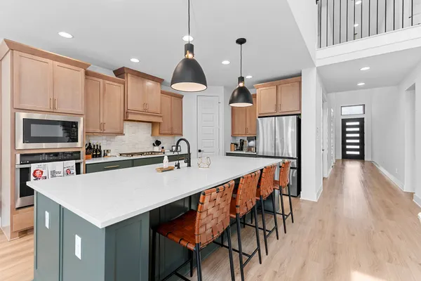 a kitchen with stainless steel appliances a table chairs refrigerator and microwave