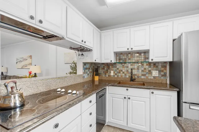 a kitchen with kitchen island granite countertop a sink stainless steel appliances and white cabinets