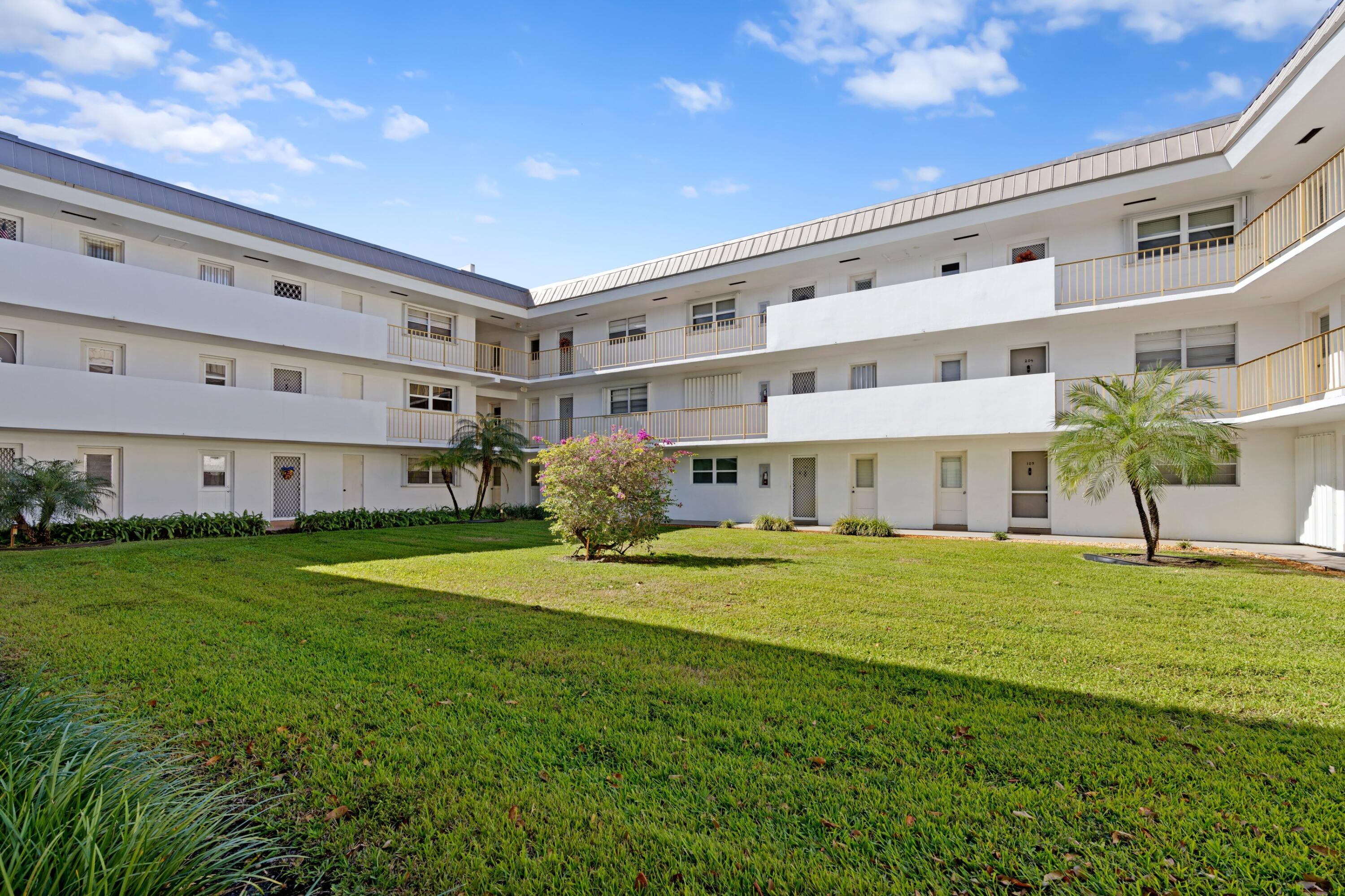 5501 Northwest 2nd Avenue, Unit 213 Boca Raton, FL 33487 - Photo 16 of 17 a view of a big building with a big yard and large tree
