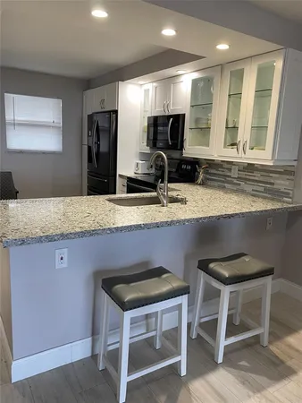 a kitchen with kitchen island granite countertop a sink and a refrigerator