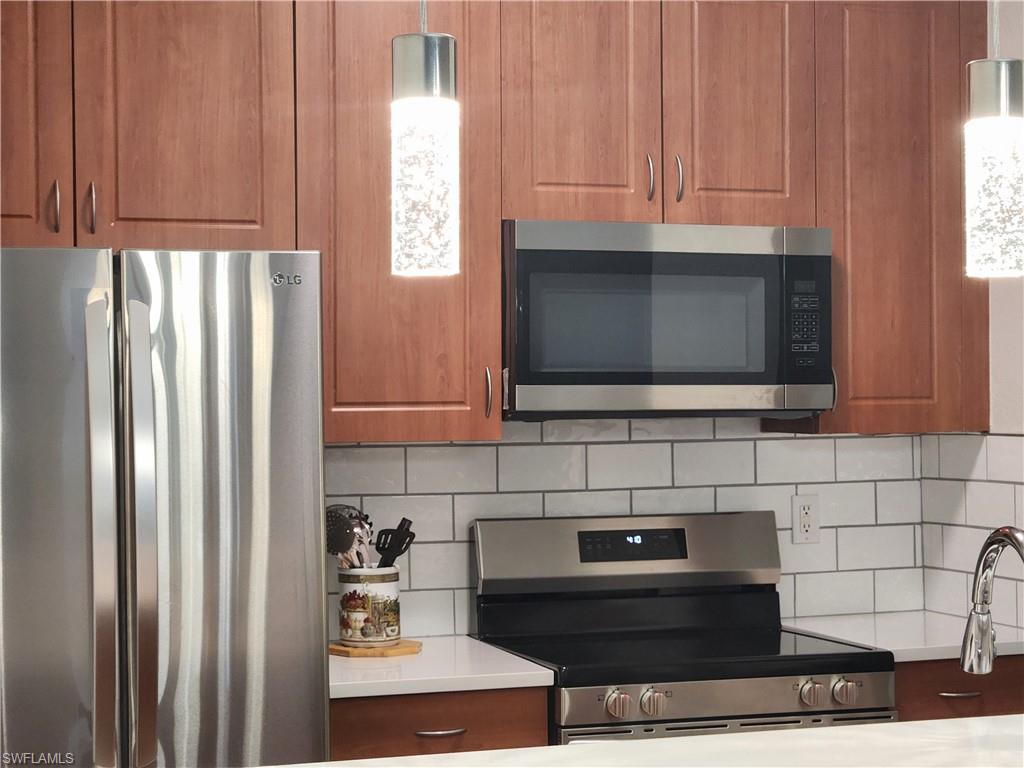7512 Bristol Circle Naples, FL 34120 - Photo 5 of 22 a kitchen with stainless steel appliances a stove a microwave and a refrigerator