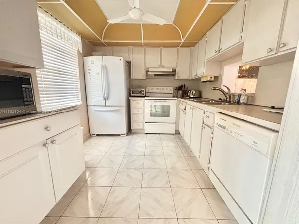 a kitchen with granite countertop a refrigerator a stove a microwave and cabinets