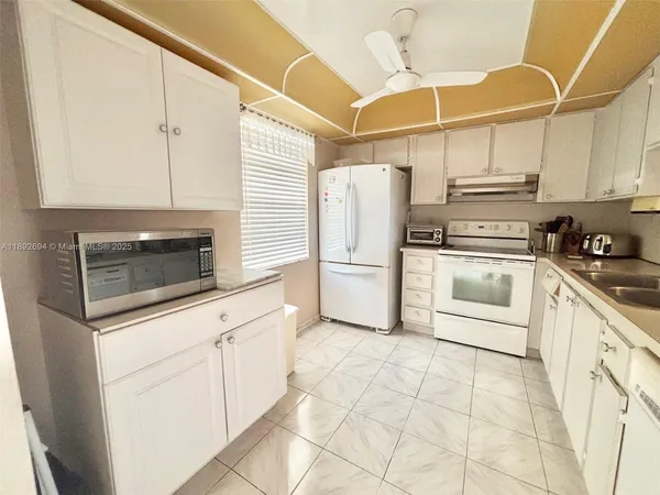 a kitchen with white cabinets and white appliances