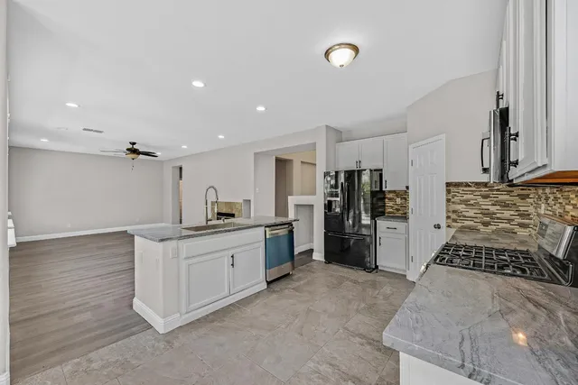 a kitchen with stainless steel appliances kitchen island granite countertop a refrigerator and a stove top oven