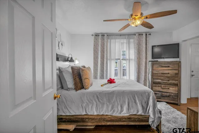 a bedroom with a bed a chandelier and a flat tv screen