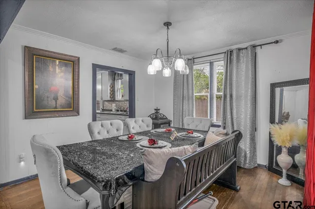 a dining room with wooden floor a chandelier a wooden table and chairs