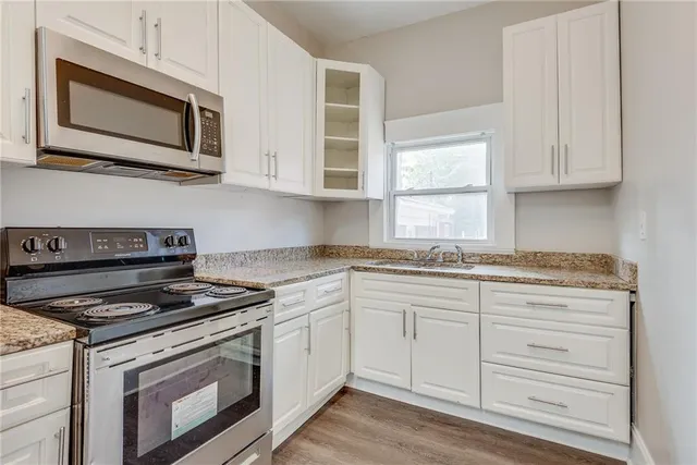 a kitchen with granite countertop white cabinets stainless steel appliances and a window