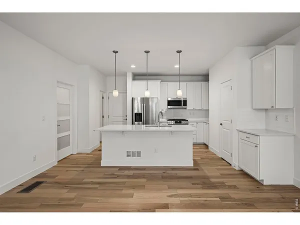 a view of kitchen with kitchen island white cabinets and stainless steel appliances
