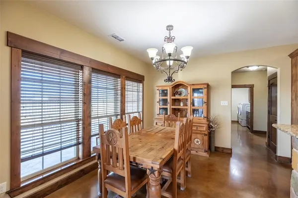 a view of a dining room with furniture a kitchen and chandelier