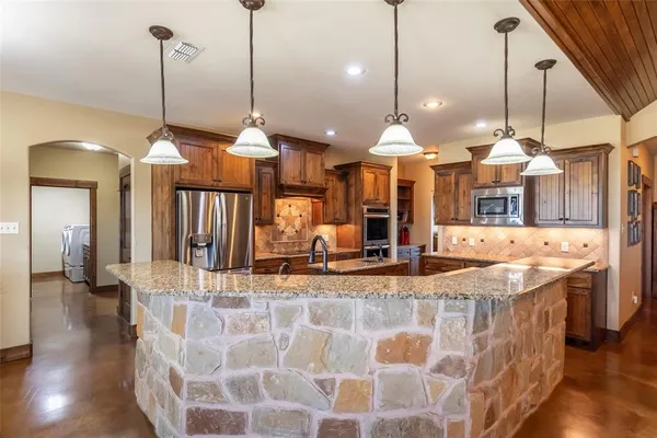 a large kitchen with kitchen island a counter space a sink appliances and wooden floor