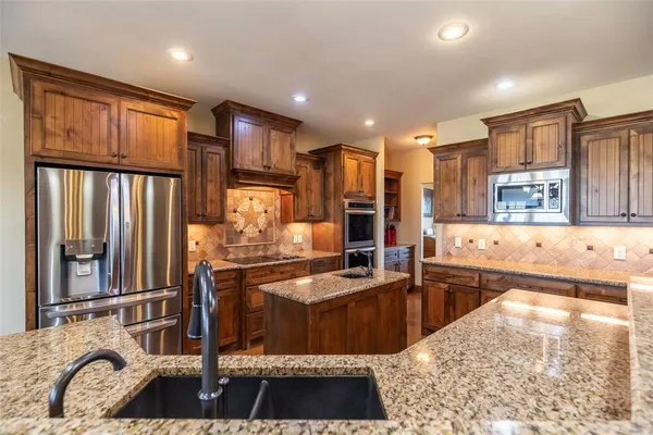 a kitchen with stainless steel appliances granite countertop a refrigerator stove and sink