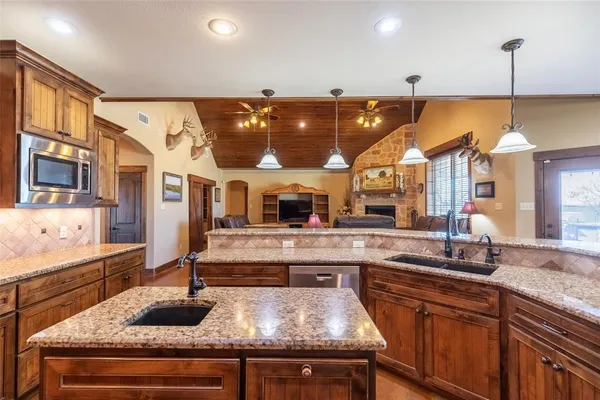 a kitchen with stainless steel appliances granite countertop a sink a stove and a wooden cabinets