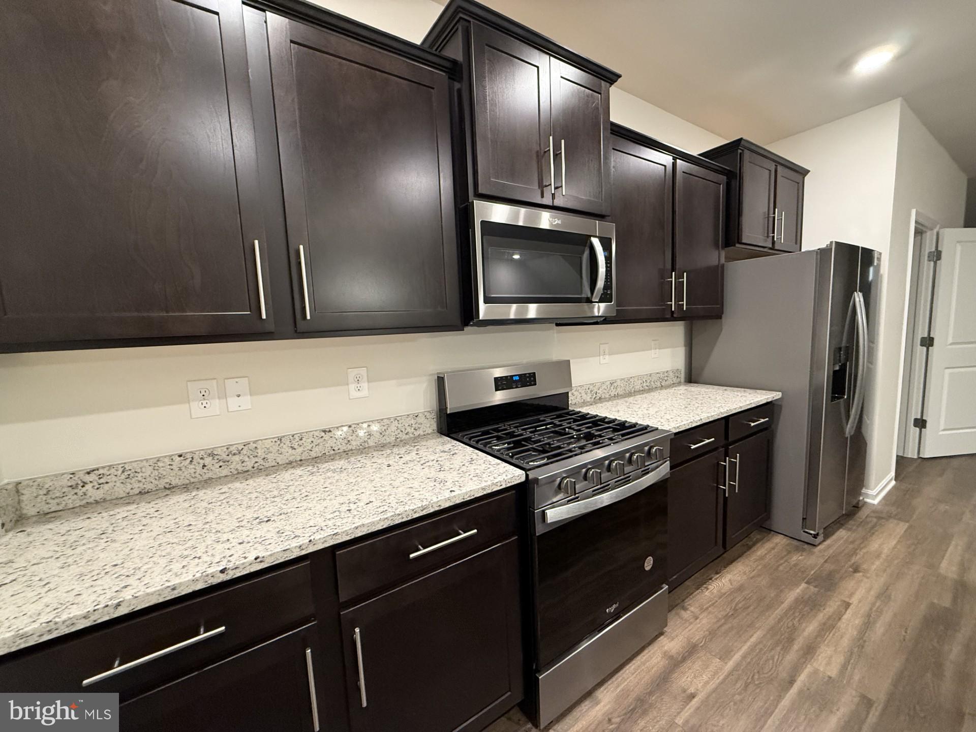 742 Compass Way Frederick, MD 21701 - Photo 11 of 30 a kitchen with granite countertop cabinets stainless steel appliances and wooden floor
