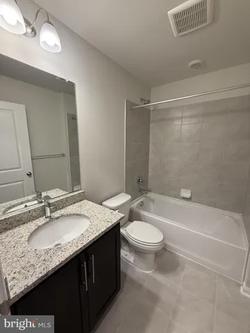 a bathroom with a granite countertop sink a toilet a mirror a bathtub and shower
